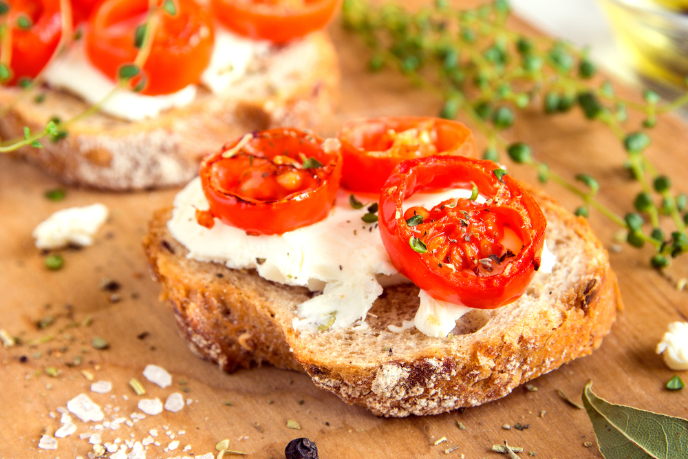 Sliced tomato roasted on goat cheese and a slice of bread