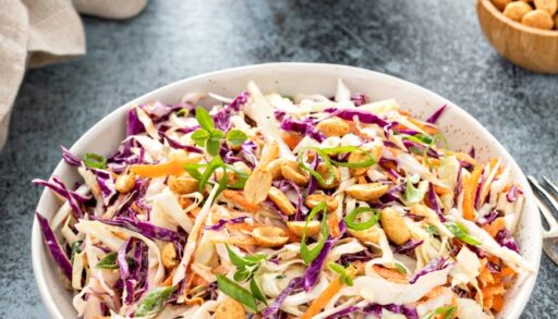 Creamy coleslaw in bowl with a side of dressing