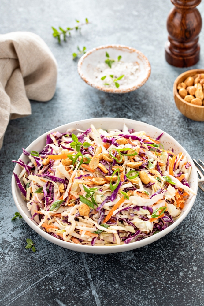 Creamy coleslaw in bowl with a side of dressing