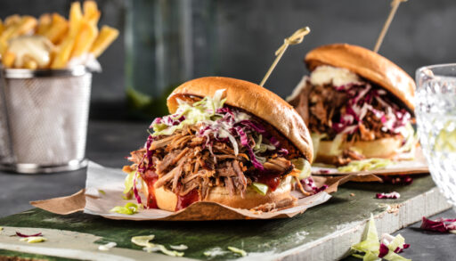 Two spicy pulled pork burgers on tray with a side of fries