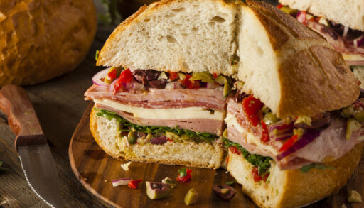 Muffaletta sandwich with meat, olives, and cheese on a cutting board