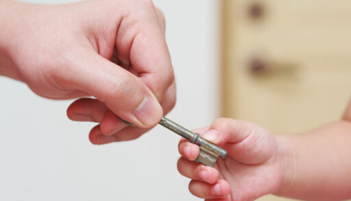 Parent handing a house key to a child.