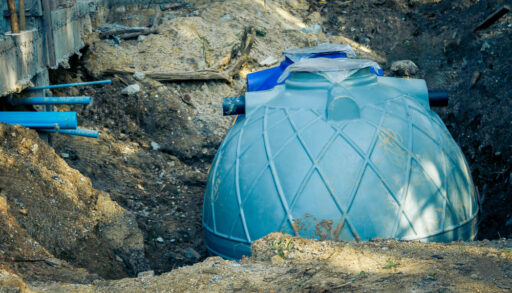 Plastic septic holding tank surrounded by dug up dirt.