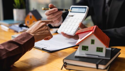 House broker calculating property value with hand pointing to calculator.