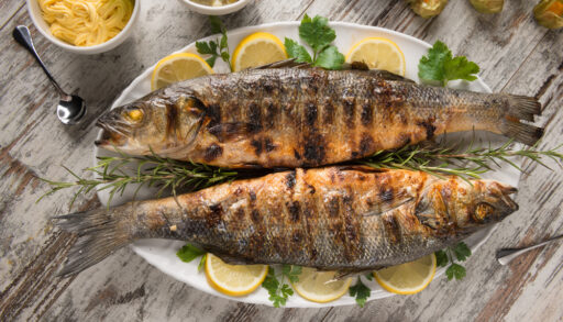 Grilled bass on a plate decorated with parsley and lemon.