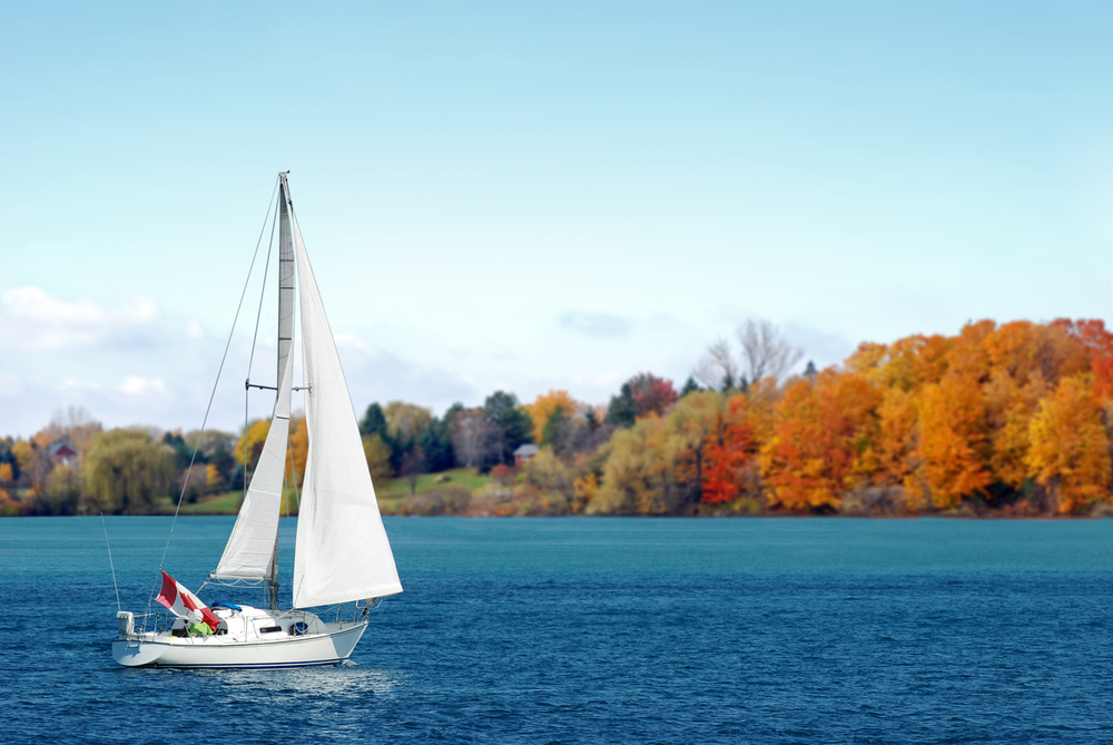 Sailboat with a Canadian flag on lake.
