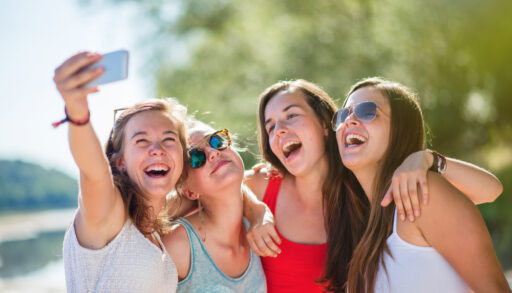 Four teenage girls taking a photo by a lake together.