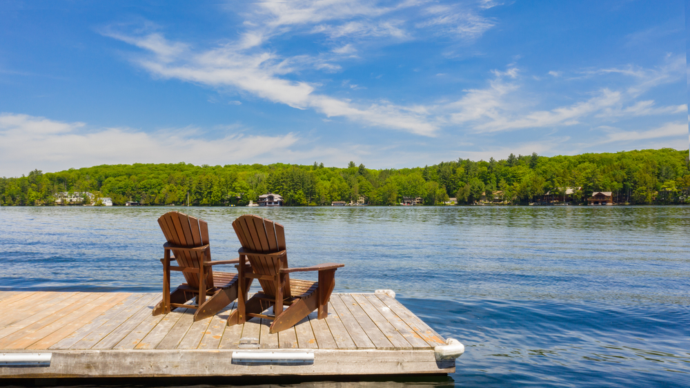 Two Muskoka chairs on a dock looking out over the water.