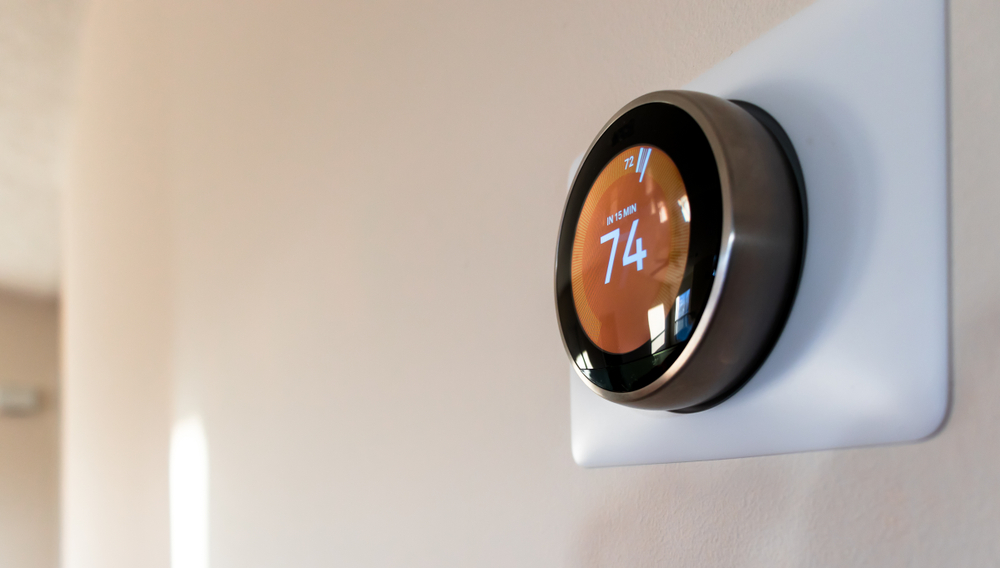 Smart home thermostat with an orange screen.