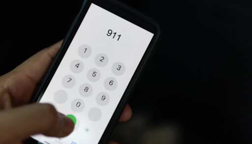 Person holding a phone and dialling 911.