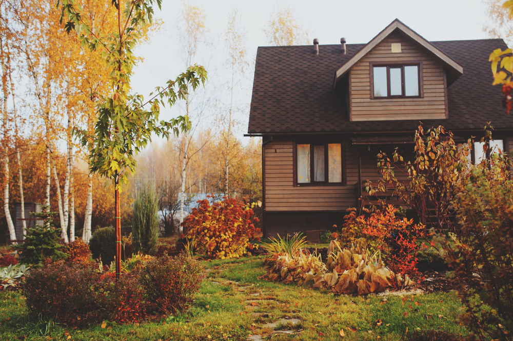 Small cottage near a lake surrounded by fall foliage.