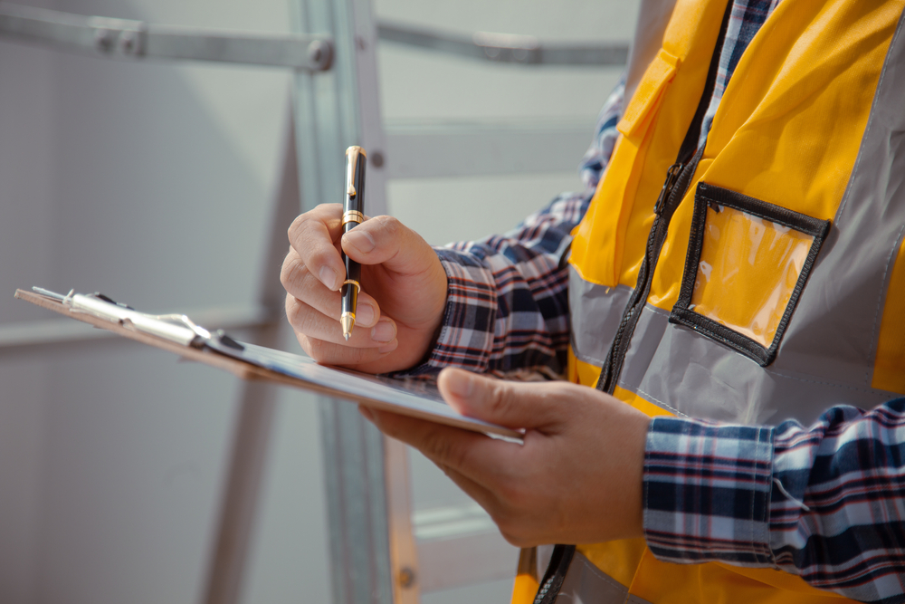 Man in an orange vest going through a checklist.