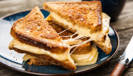 Grilled cheese sandwiches stacked on a blue plate.