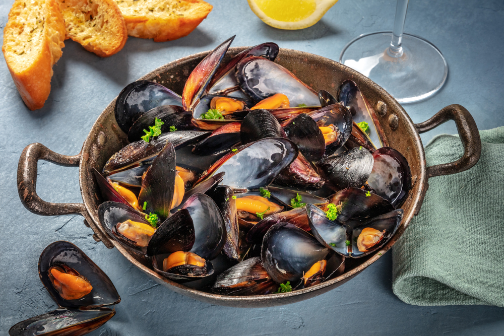 Cooked blue mussels in a cast iron pan.