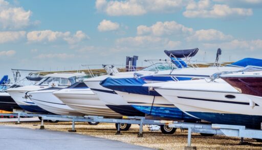 Row of new boats lined up along a paved road.