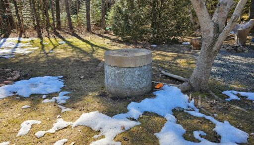 Large dug well underneath a tree on a lawn.