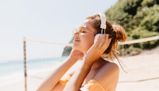 Woman with headphones on listening to music on a beach.