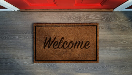 Overhead view of a welcome mat in front of a red door.