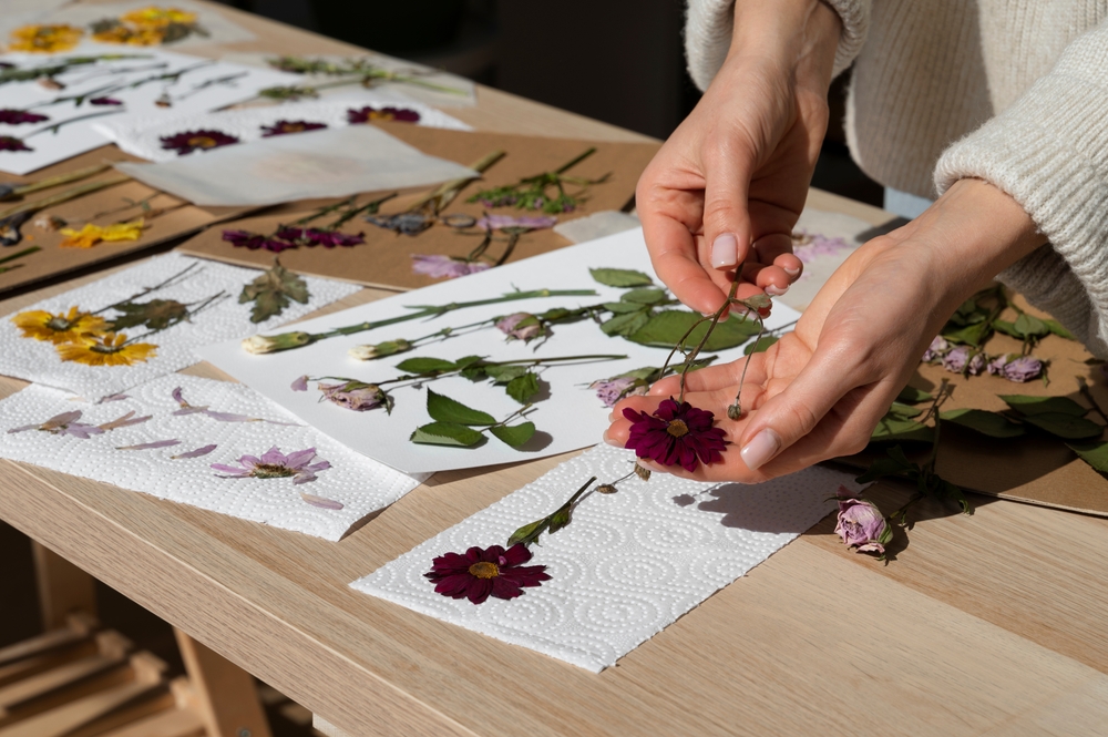 Woman laying pressed flowers on paper.