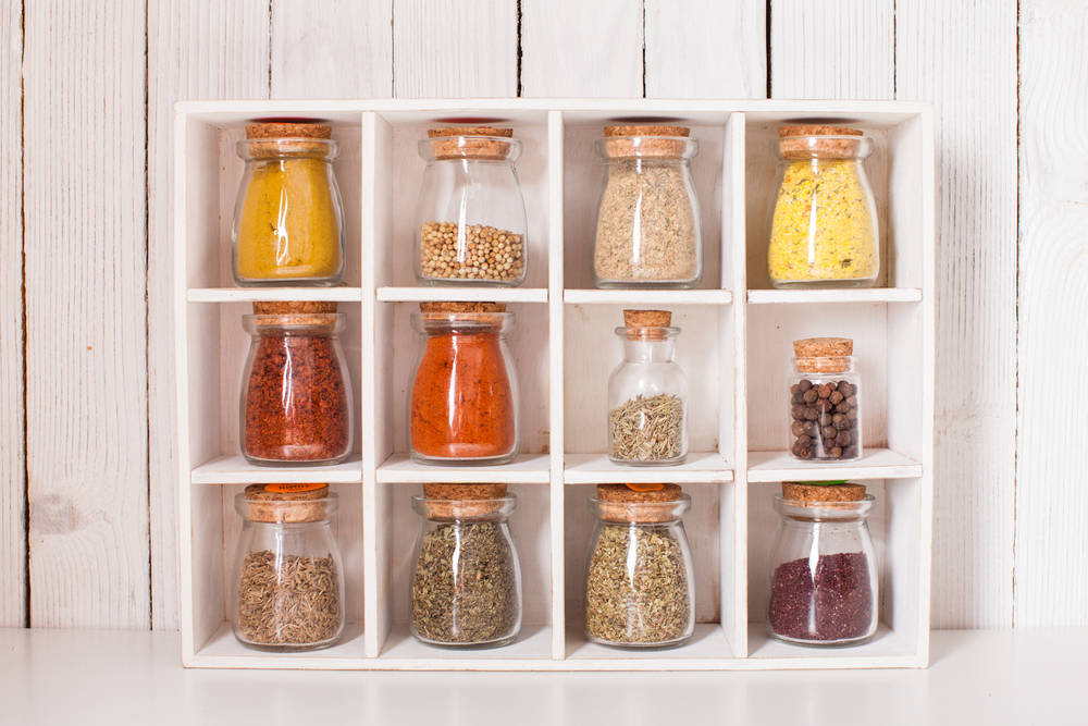 Repurposed wooden shelf containing different coloured jars of spices.