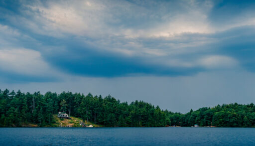 View of storm clouds forming over a lake and cottage.