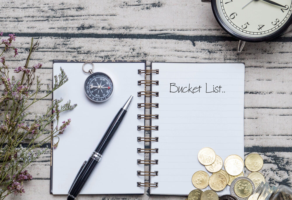 Notebook on a wooden table with a pen and a compass.