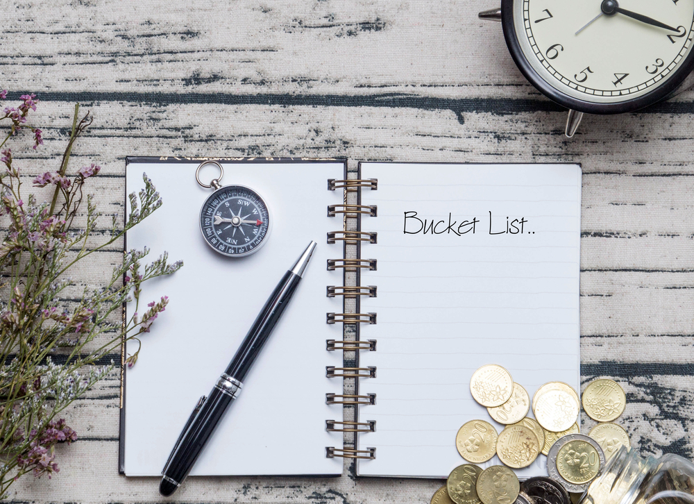 Notebook on a wooden table with a pen and a compass.