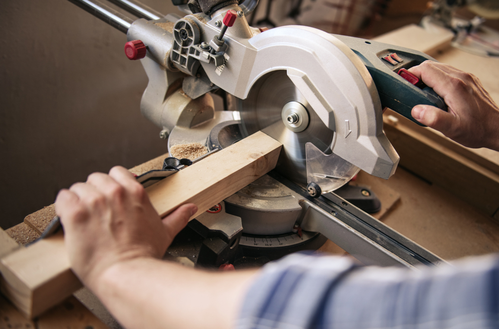 Carpenter using a mitre saw to cut a piece of wood.