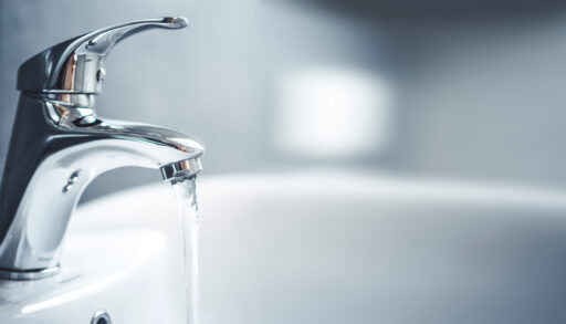 Clear water running out of a silver faucet.
