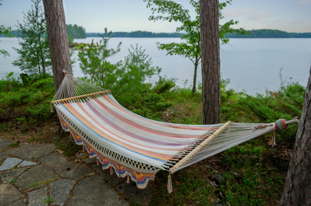 Colourful hammock hanging next to a lake.
