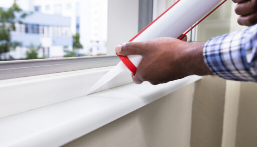 Man applying caulking to a window.