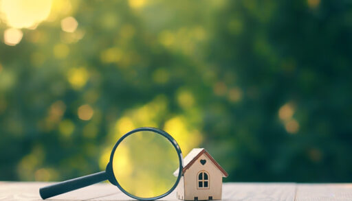 mini house and magnifying glass, natural green background. House searching, choice of location for construction, of mortgage, rental housing.