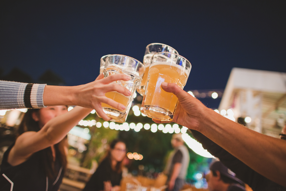 Three people raising their beer glasses together.