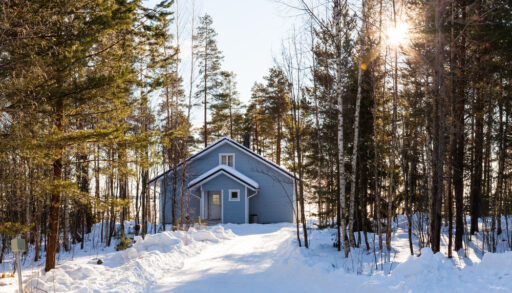 Grey cottage in the middle of a forest in winter.