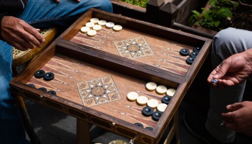 Two men playing backgammon on a folding table.