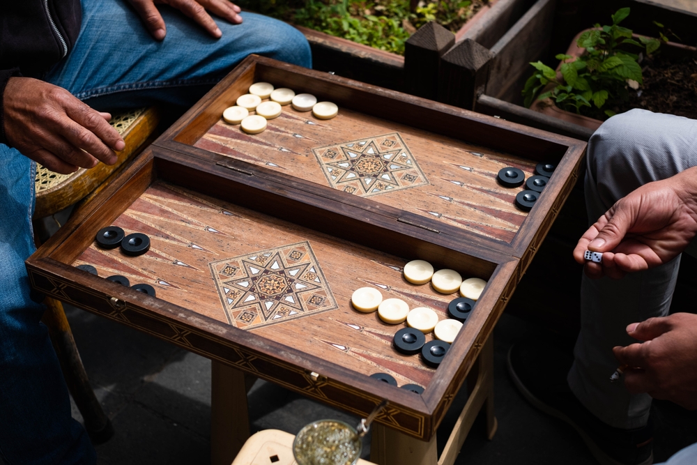 Two men playing backgammon on a folding table.