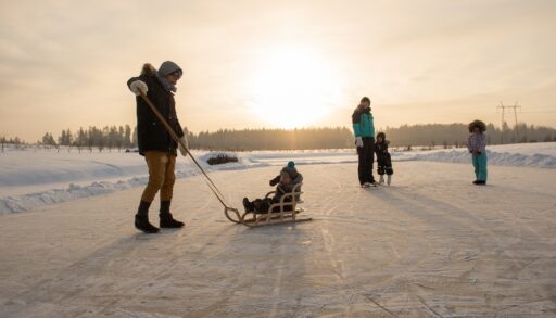 Family of five on an outdoor skating rink at sunset.