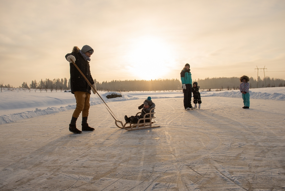 Family of five on an outdoor skating rink at sunset.
