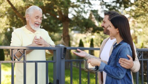 Young man and woman talking with an older man next to a fence.