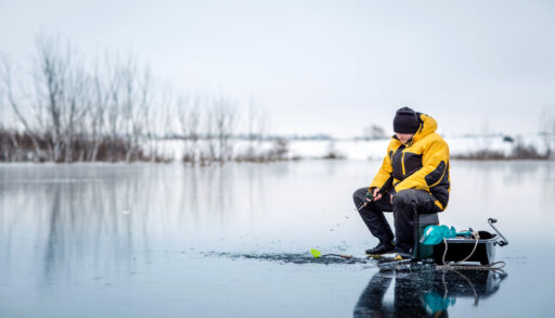 Man ice fishing on a frozen lake.