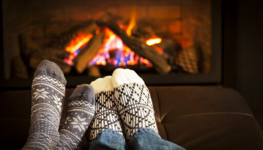 Couple putting their feet in front of a fire together.
