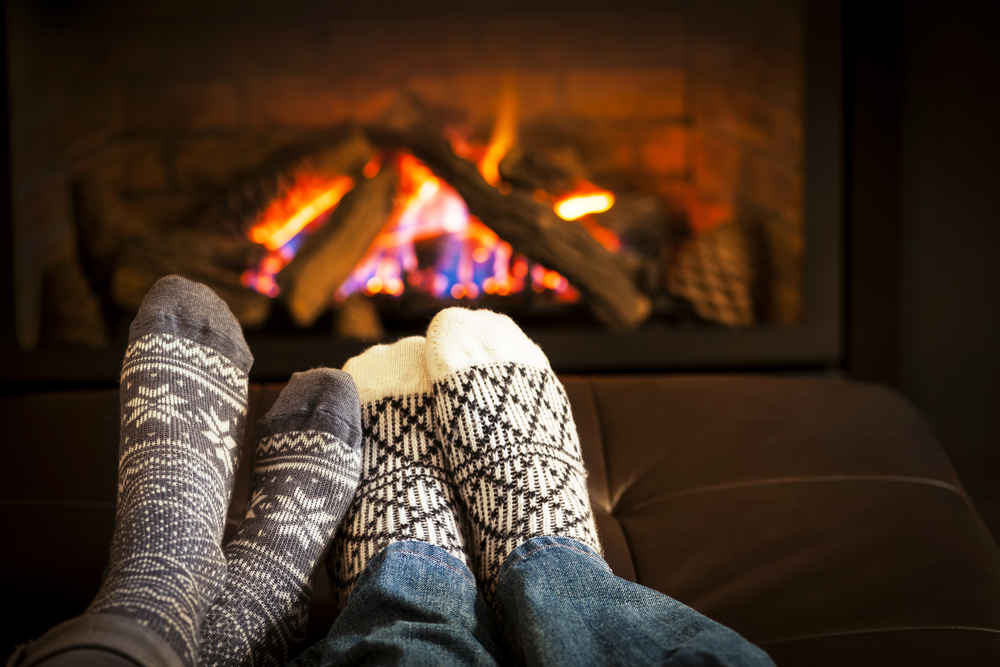 Couple putting their feet in front of a fire together.