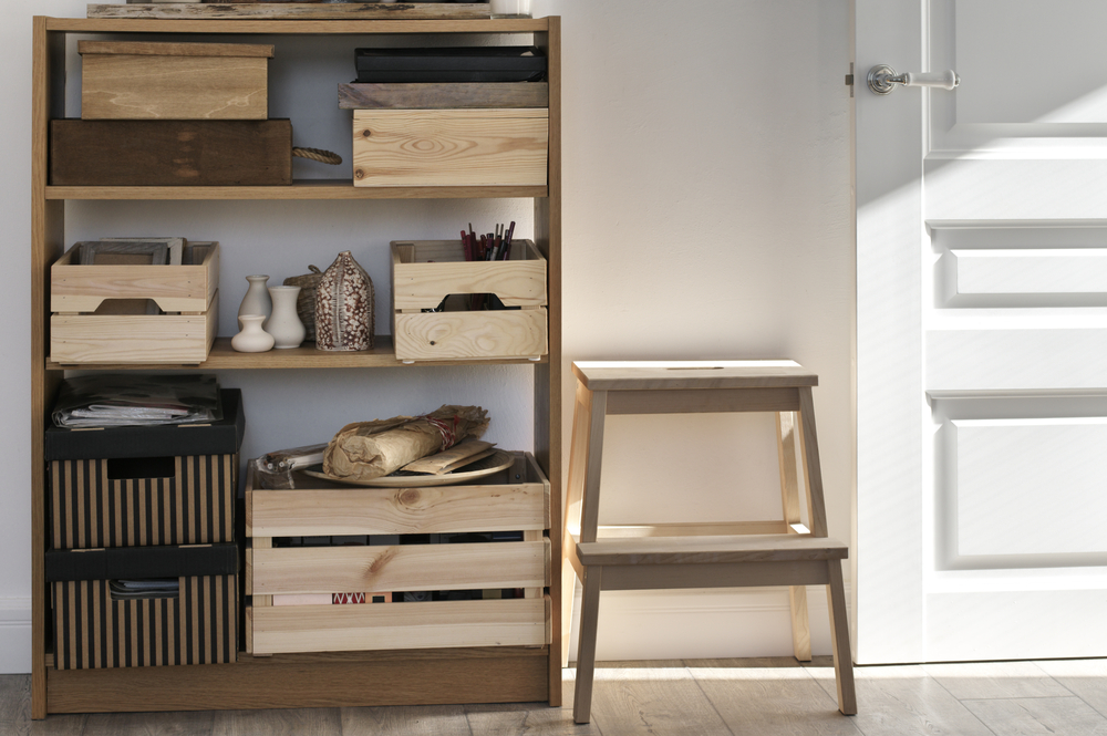 Wooden crates organized on a wood shelf near a step stool and door.
