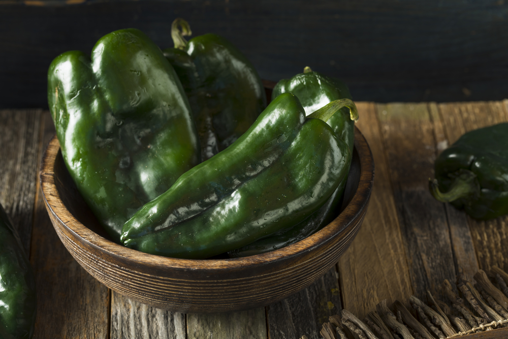 Green poblano peppers in a wooden bowl.