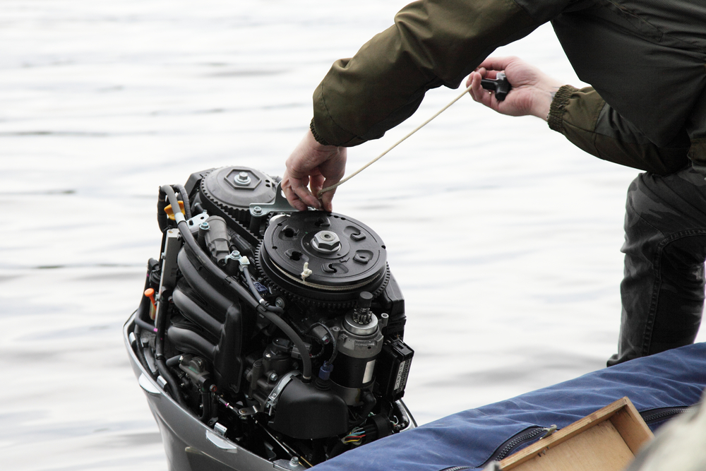 Person adjusting an outboard motor on a boat.