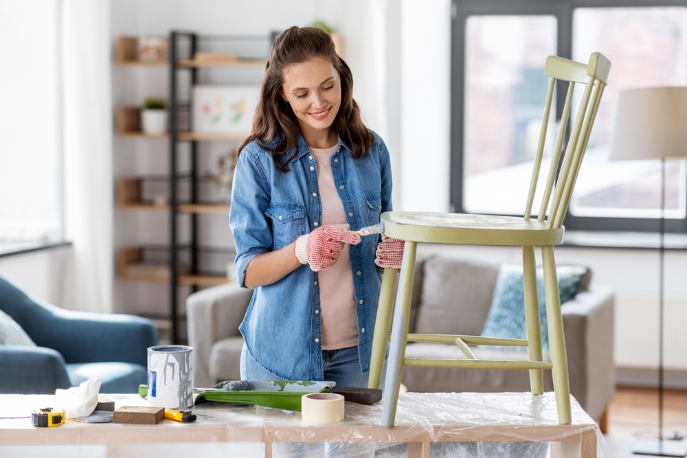 Woman painting a chair green on top of a table.