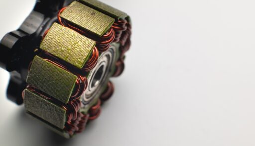 Disassembled brushless motor with gold plates and red wires.