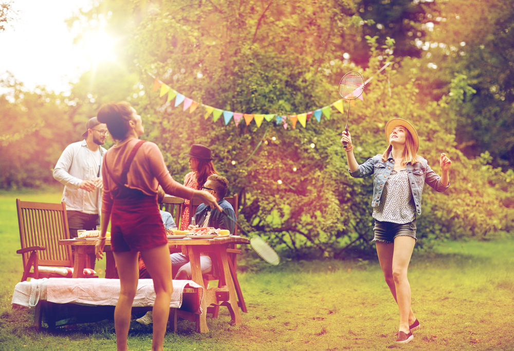 Group of people having an outdoor party and playing badminton.