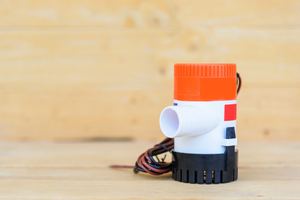 Orange, white and black bilge pump against a wood background.