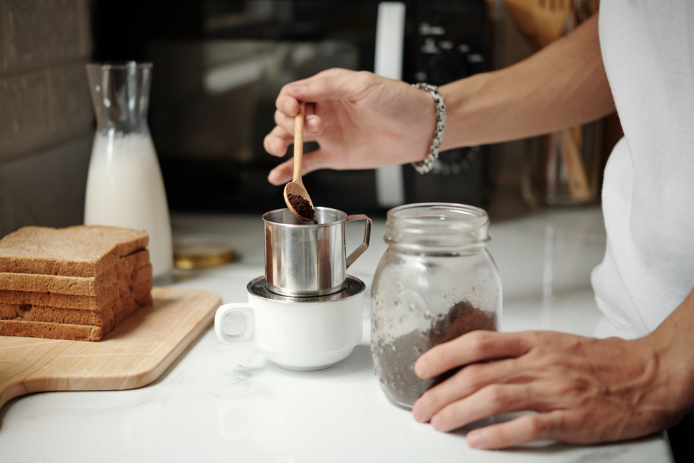 Man making a cup of coffee by putting coffee grounds into a cup.